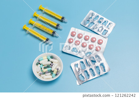 Empty and used medicine blister packs with pink pills and syringes. Empty and used medicine blister packs with pink pills and syringes. 121262242