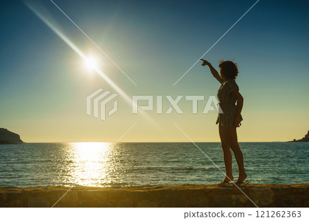 Tourist woman on sea shore enjoying sunset 121262363
