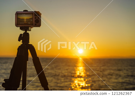 Camera taking picture film of sunset over sea surface 121262367