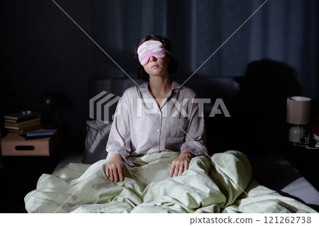 Sleepy woman sitting in bed during night, she suffering from sleepwalking 121262738
