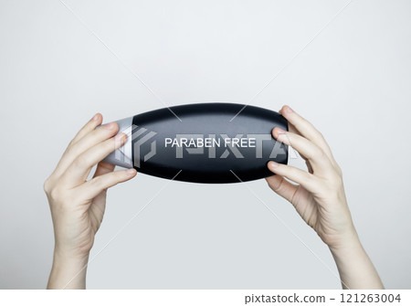 Female hands holding a can of shampoo, where it is written paraben free, no paraben. The concept of safe composition of shampoo without aggressive components Female hands holding a can of shampoo, where it is written paraben free, no paraben. The concept of safe composition of shampoo without aggressive components 121263004