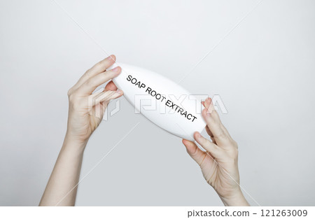 Female hands hold a bottle of shampoo, on which the ingredient is written - soap root extract. The concept of safe composition of organic shampoos 121263009