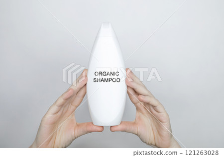 Female hands holding a bottle with the words - organic shampoo. Concept of safe composition and ingredients of environmentally friendly cosmetics and detergents 121263028