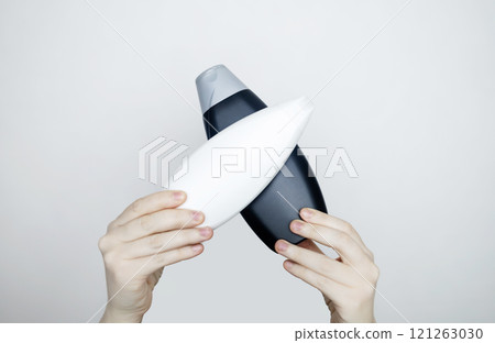 Female hands holding a can of shampoo with a blank label. White background, space for text. Composition of shampoo or conditioner 121263030