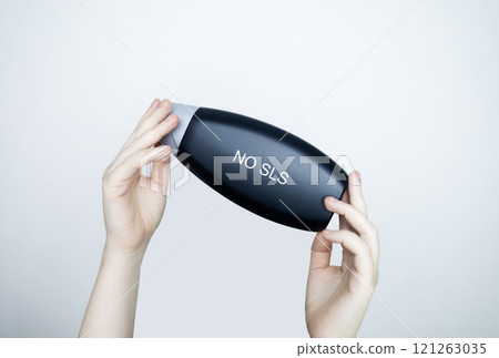 Female hands holding a can of shampoo, where it is written no sls, sls free. The concept of safe composition of shampoo without aggressive components Female hands holding a can of shampoo, where it is written no sls, sls free. The concept of safe composition of shampoo without aggressive components 121263035