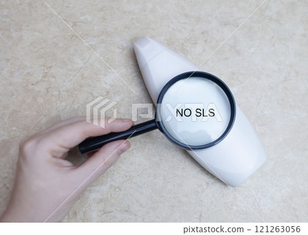Female hands holding a can of shampoo, where it is written no sls, sls free. The concept of safe composition of shampoo without aggressive components 121263056
