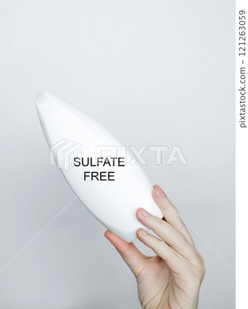Female hands holding a can of shampoo, where it is written sulfate free, no sulfates. The concept of safe composition of shampoo without aggressive components 121263059
