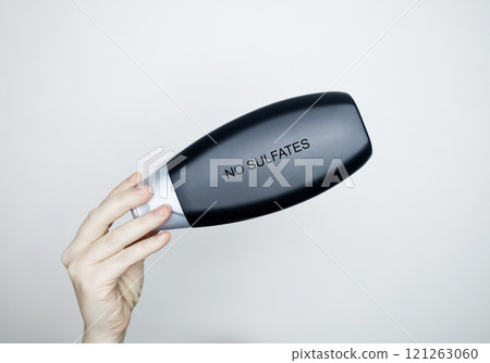 Female hands holding a can of shampoo, where it is written sulfate free, no sulfates. The concept of safe composition of shampoo without aggressive components Female hands holding a can of shampoo, where it is written sulfate free, no sulfates. The concept of safe composition of shampoo without aggressive components 121263060