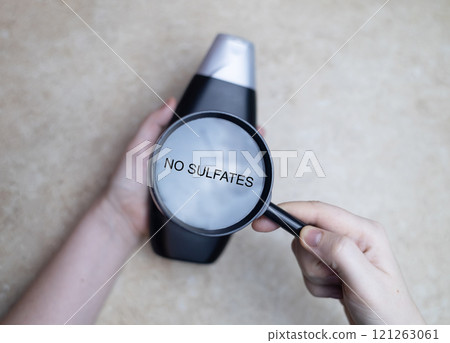 Female hands holding a can of shampoo, where it is written sulfate free, no sulfates. The concept of safe composition of shampoo without aggressive components Female hands holding a can of shampoo, where it is written sulfate free, no sulfates. The concept of safe composition of shampoo without aggressive components 121263061