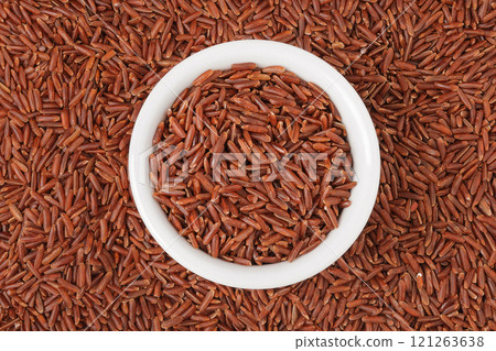red rice in a ceramic bowl as a background. Top view. Flat lay 121263638