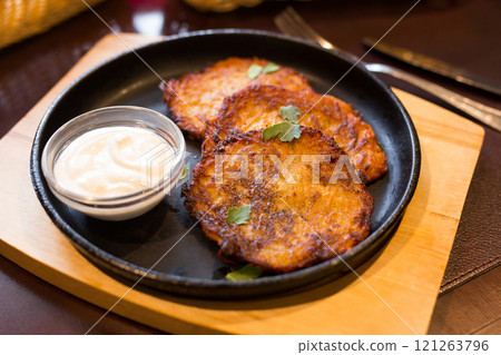 Potato pancakes with sour cream on frying pan 121263796