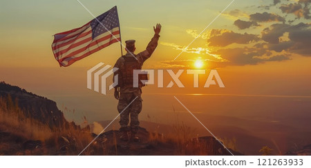 Soldier standing on a hill at sunset holding the American flag 121263933