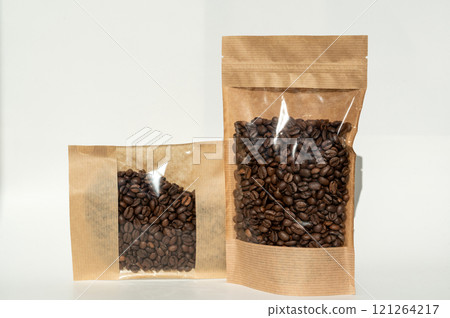 A kraft paper bag with coffee beans for viewing with a highlighted shadow lies on a white background A kraft paper bag with coffee beans for viewing with a highlighted shadow lies on a white background 121264217