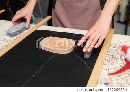 Female artisan setting up woodblock for printmaking on black fabric Female artisan setting up woodblock for printmaking on black fabric 121264224