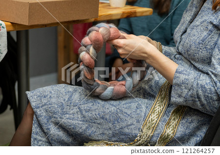 Caucasian female creating a handmade woven wool wreath with braided yarn 121264257