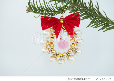 Festive pearl and gold christmas wreath ornament on pine branch Festive pearl and gold christmas wreath ornament on pine branch 121264296
