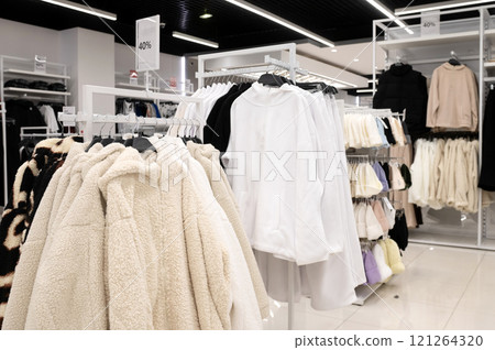 Casual jackets, hoodies, and coats displayed on racks in a clothing store with a 40 discount sign. Casual jackets, hoodies, and coats displayed on racks in a clothing store with a 40 discount sign. 121264320