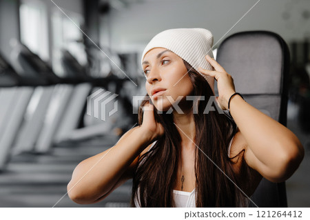 Portrait confident beautiful young brunette woman is wearing white beanie Portrait confident beautiful young brunette woman is wearing white beanie 121264412