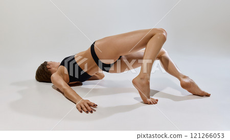 Woman poses gracefully on floor emphasizing strength, elegance, and fitness as natural beauty shines through poised expression and toned body. Woman poses gracefully on floor emphasizing strength, elegance, and fitness as natural beauty shines through poised expression and toned body. 121266053