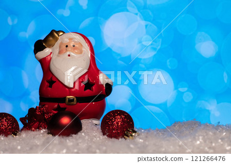 Ceramic Santa Claus statue and christmas tree toys standing on snow Ceramic Santa Claus statue and christmas tree toys standing on snow 121266476