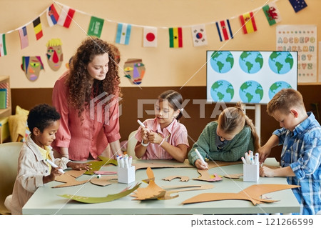 Multiethnic group of children cutting cardboard during art and craft class making dinosaur figures and learning about Earth history copy space 121266599