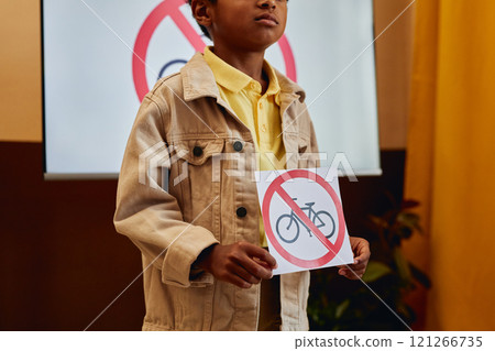 Close up of young African American boy holding No bicycles sign while giving presentation on road safety in primary school classroom copy space Close up of young African American boy holding No bicycles sign while giving presentation on road safety in primary school classroom copy space 121266735
