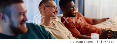 Header image of three friends sitting on couch watching TV together and smiling holding beer glasses, copy space Header image of three friends sitting on couch watching TV together and smiling holding beer glasses, copy space 121267458