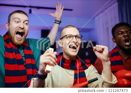 Closeup portrait of excited sports fans cheering and screaming while celebrating win and wearing matching team scarves Closeup portrait of excited sports fans cheering and screaming while celebrating win and wearing matching team scarves 121267473
