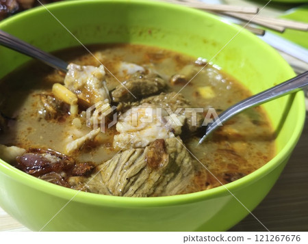 A bowl of hearty Gulai Kambing, a rich Indonesian soup brimming with tender goat meat, vegetables, and spices. A bowl of hearty Gulai Kambing, a rich Indonesian soup brimming with tender goat meat, vegetables, and spices. 121267676