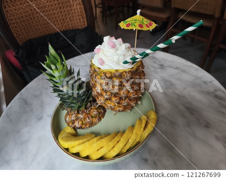 A refreshing pineapple cocktail served in a hollowed out pineapple. 121267699