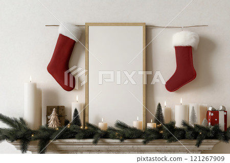 Fireplace decorated for Christmas with a garland, candles, Christmas socks and a blank frame hanging above 121267909