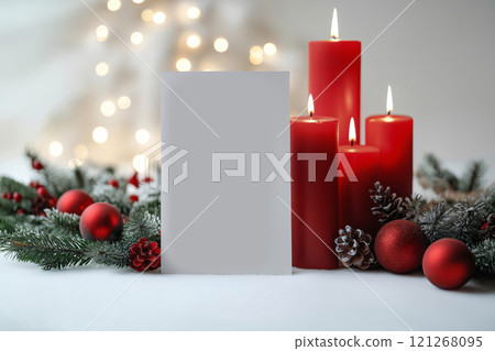 Christmas menu standing next to burning candles, a pine branch and red Christmas baubles, with Christmas lights in the background 121268095