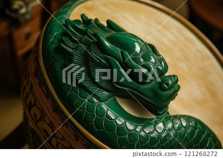 Close up on a green wooden dragon head carving decorating a round surface, Asian style interior design 121268272