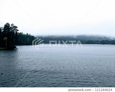 a Norwegian lake surrounded by trees on a dark rainy day a Norwegian lake surrounded by trees on a dark rainy day 121269024