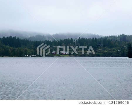 a Norwegian lake surrounded by trees on a dark rainy day 121269046