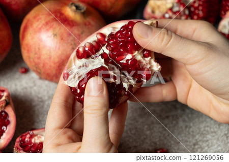 Hands open the pomegranate, separation into parts, pomegranates grains Hands open the pomegranate, separation into parts, pomegranates grains 121269056