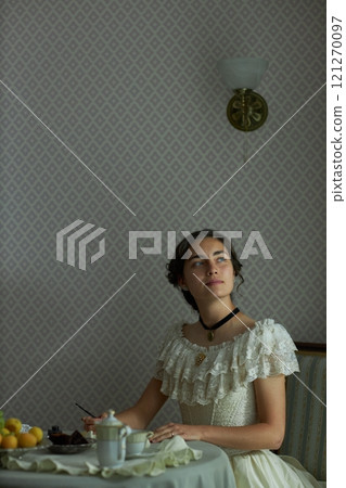 Vertical portrait of classic young lady in vintage lace dress writing letter and looking up pensively while sitting at elegant table with tea set, copy space Vertical portrait of classic young lady in vintage lace dress writing letter and looking up pensively while sitting at elegant table with tea set, copy space 121270097
