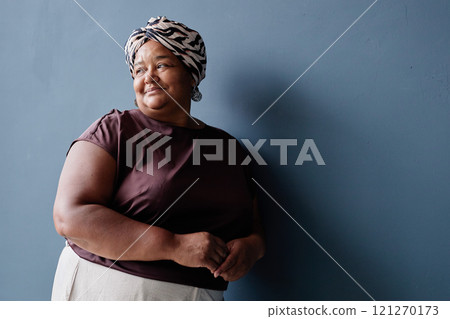 Minimal waist up portrait of authentic senior African American woman wearing headscarf and looking way on blue background with soft natural daylight, copy space Minimal waist up portrait of authentic senior African American woman wearing headscarf and looking way on blue background with soft natural daylight, copy space 121270173