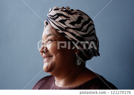 Minimal side view portrait of senior African American woman smiling kindly with soft natural light on blue background in studio and wearing traditional headscarf Minimal side view portrait of senior African American woman smiling kindly with soft natural light on blue background in studio and wearing traditional headscarf 121270176