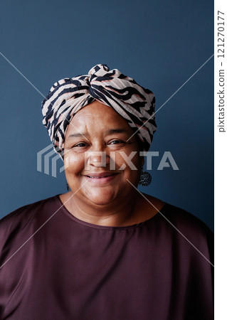 Vertical front view portrait of senior African American woman wearing headscarf and looking at camera with smile on blue background in studio Vertical front view portrait of senior African American woman wearing headscarf and looking at camera with smile on blue background in studio 121270177