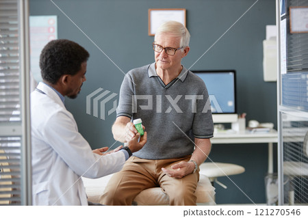 Portrait of Caucasian senior man taking bottle with prescription pills during consultation in clinic and treating chronic illness, copy space 121270546