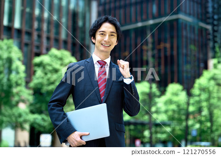Businessman standing with a laptop in an office building Businessman standing with a laptop in an office building 121270556