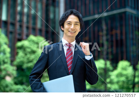 Businessman standing with a laptop in an office building Businessman standing with a laptop in an office building 121270557