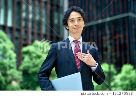 Businessman standing with a laptop in an office building Businessman standing with a laptop in an office building 121270558
