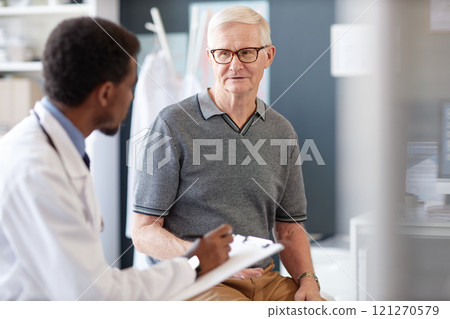 Portrait of Caucasian senior man talking to doctor during consultation in clinic and explaining symptoms and health concerns, copy space Portrait of Caucasian senior man talking to doctor during consultation in clinic and explaining symptoms and health concerns, copy space 121270579