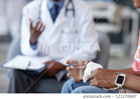 Close up of unrecognizable African American woman holding glass of water and tissue after getting bad news during consultation with doctor in medical clinic, copy space. Close up of unrecognizable African American woman holding glass of water and tissue after getting bad news during consultation with doctor in medical clinic, copy space. 121270607