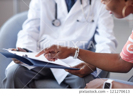 Close up of female hand pointing at clipboard asking questions to doctor during consultation in clinic, copy space Close up of female hand pointing at clipboard asking questions to doctor during consultation in clinic, copy space 121270613