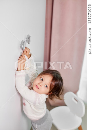 cute little child girl decorates her room before Christmas and hangs gnomes and snowmen on the door handle 121271066