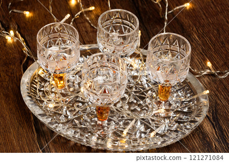 Close-up of crystal glasses on a crystal tray with Christmas tree garland. 121271084