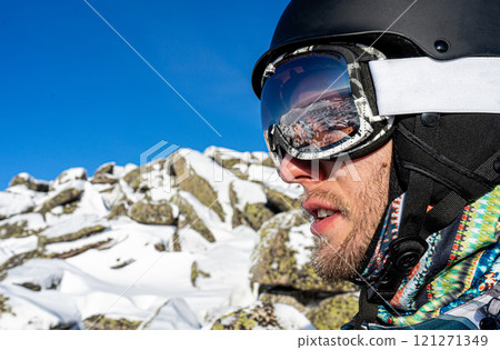 Skier's snowboarder equipment: helmet mask, glasses. Reflection in ski goggles, snowy stones. Man on ski resort Skier's snowboarder equipment: helmet mask, glasses. Reflection in ski goggles, snowy stones. Man on ski resort 121271349